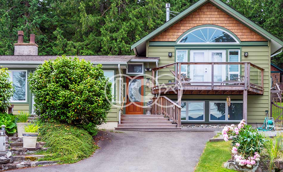 Green home with wood shingle siding in residential neighborhood.
