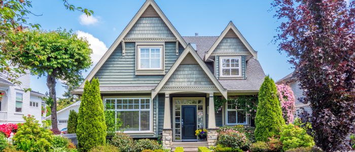 Beautiful Gray home with bright green grass on a sunny summer day.