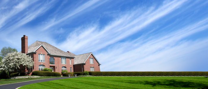 House on plot of land located in left corner of image with blue lightly clouded sky.