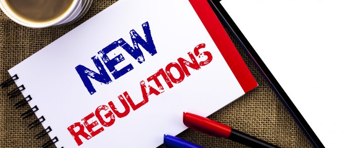 Handwriting text New Regulations. Concept meaning Change of Laws Rules Corporate Standards Specifications written Notebook Book the jute background Tablet Coffee Cup and Pens next to it.